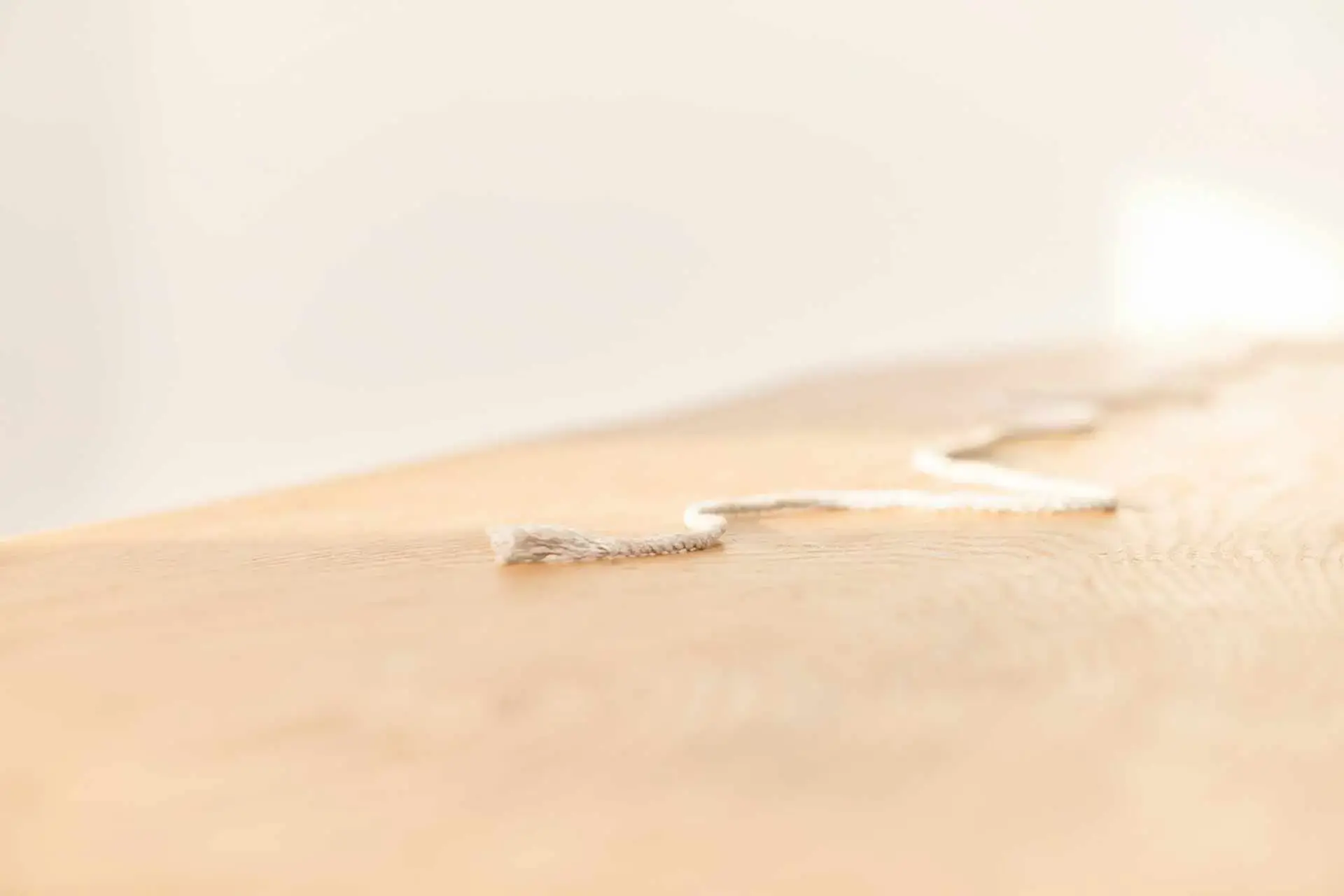 Sanfte Nahaufnahme einer hellen, minimalistischen Oberfläche mit einer feinen Schnur und warmen Beige-Tönen für Coaching für Fach- und Führungskräfte.